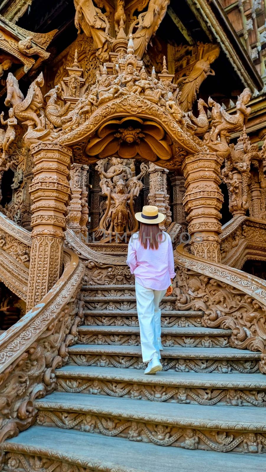 A mysterious woman in a straw hat gracefully descends a staircase with purpose, embodying elegance and adventure by fokkebok