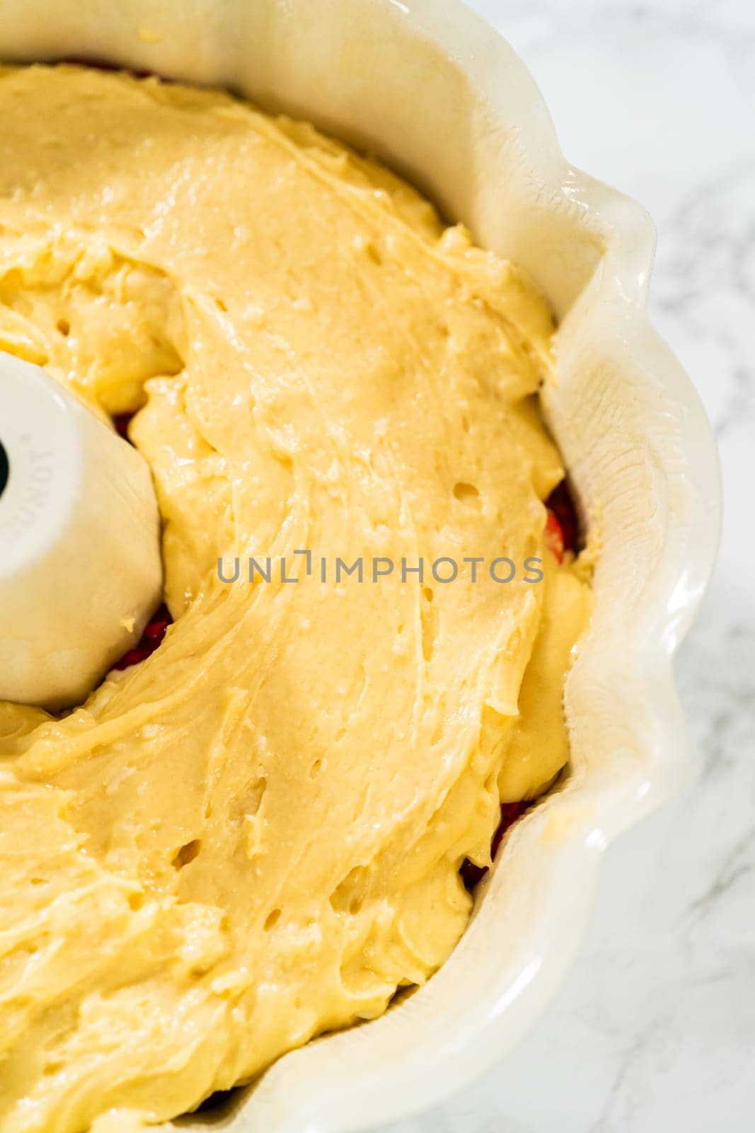 After greasing the bundt cake pan, it's time to fill it with the prepared cake batter and delightful raspberry cake filling - creating a perfect harmony of flavors.