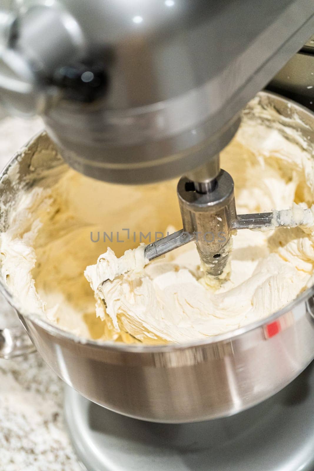 Stand mixer whips up creamy buttercream frosting to perfection, ready for dessert decorating.