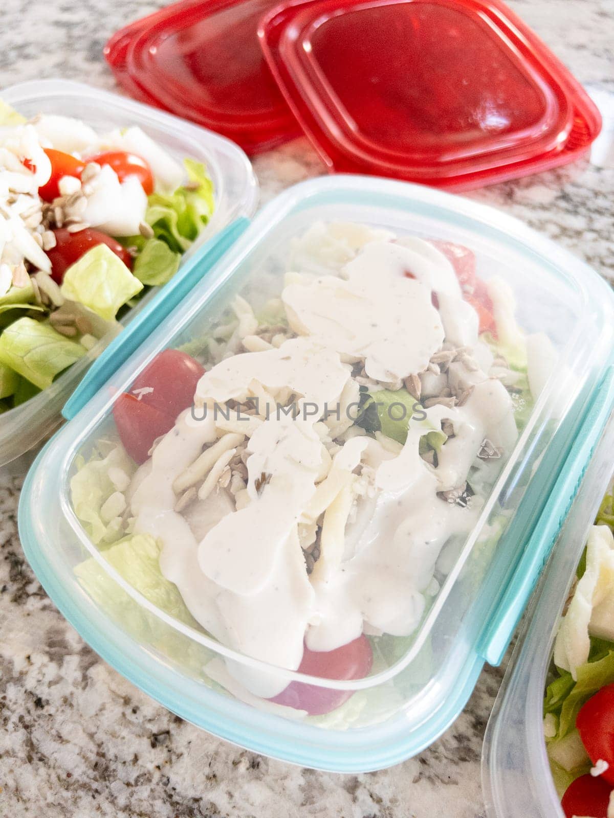 Containers filled with salad and dressing, prepared for convenient lunchtime meal prep.