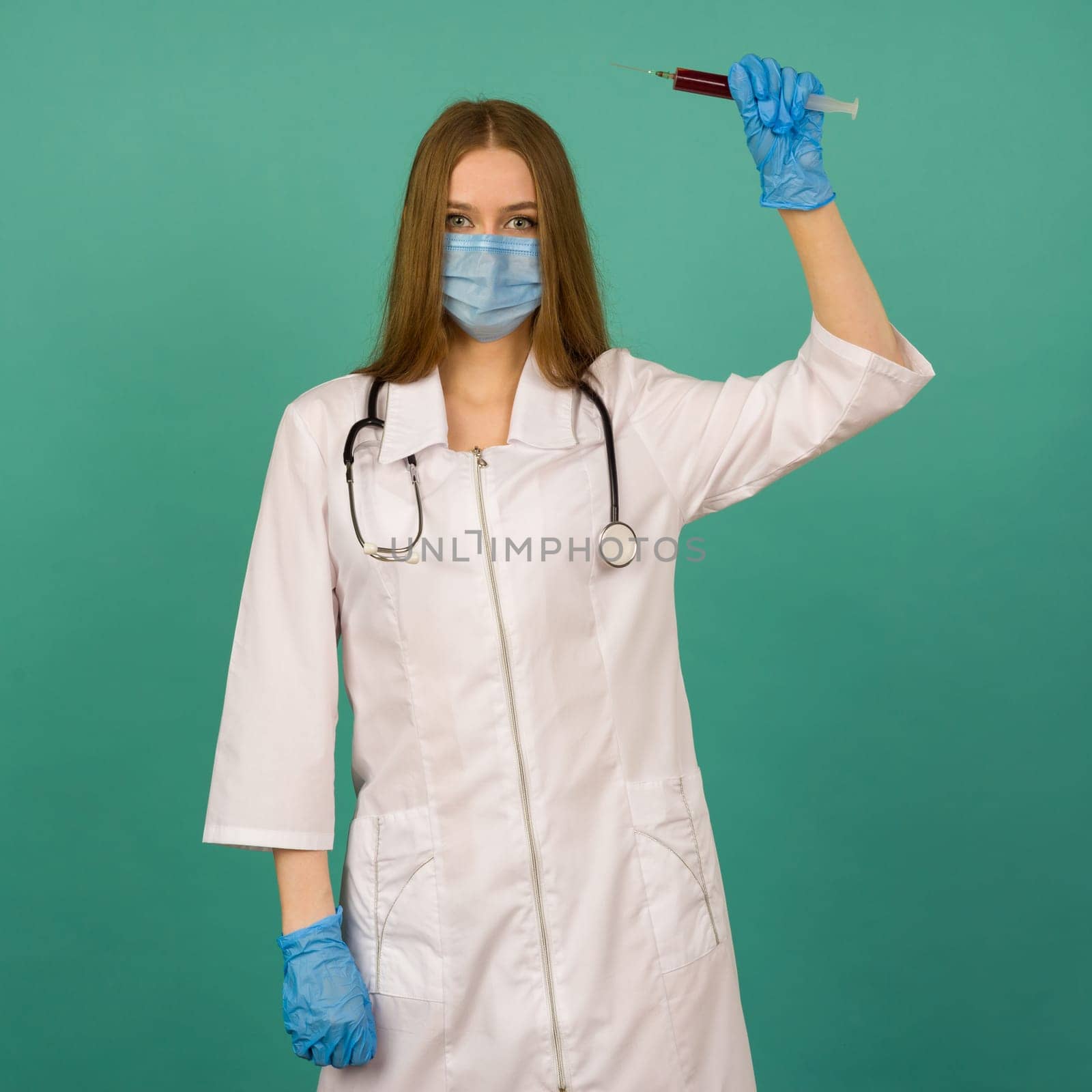 Covid19, coronavirus. Portrait of professional confident young caucasian doctor in medical mask and white coat, stethoscope over neck, with vaccine syringe in hand, fight disease by zartarn