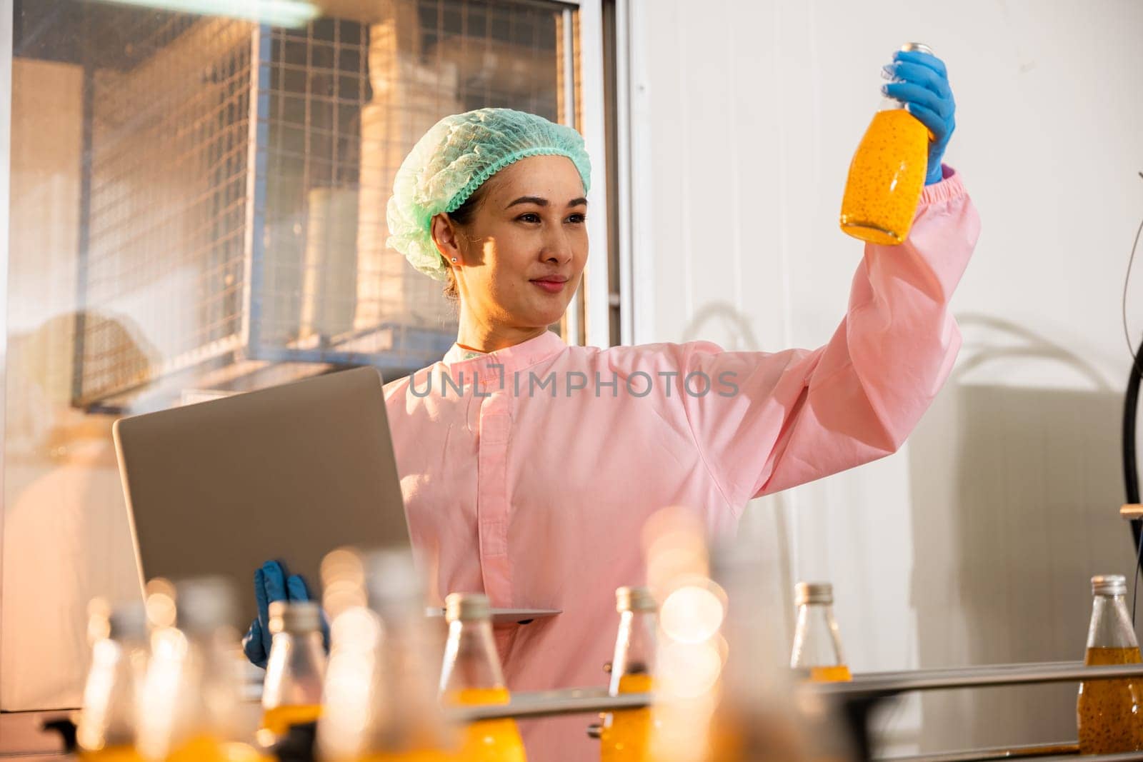 Quality inspector a woman carefully examines beverage bottles on a conveyor by Sorapop