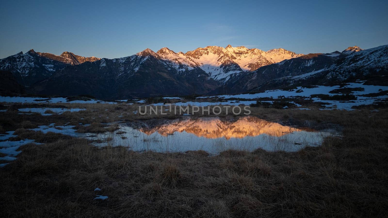 Sunset over the Pyrenees mountains with the reflection of the peaks in the water of the lake High quality 4k footage