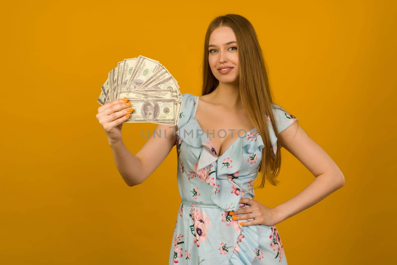 Joyful girl won the lottery and holds a fan of US dollars in her hands on a yellow background - image