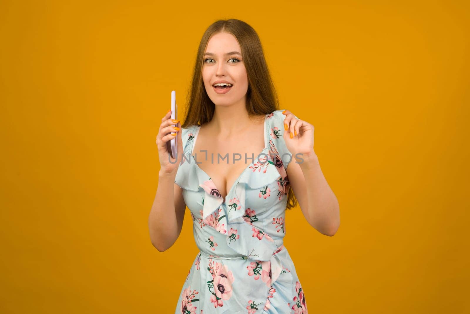 Young woman wears in sunner dress with flowers surprised by the news on a smartphone - image