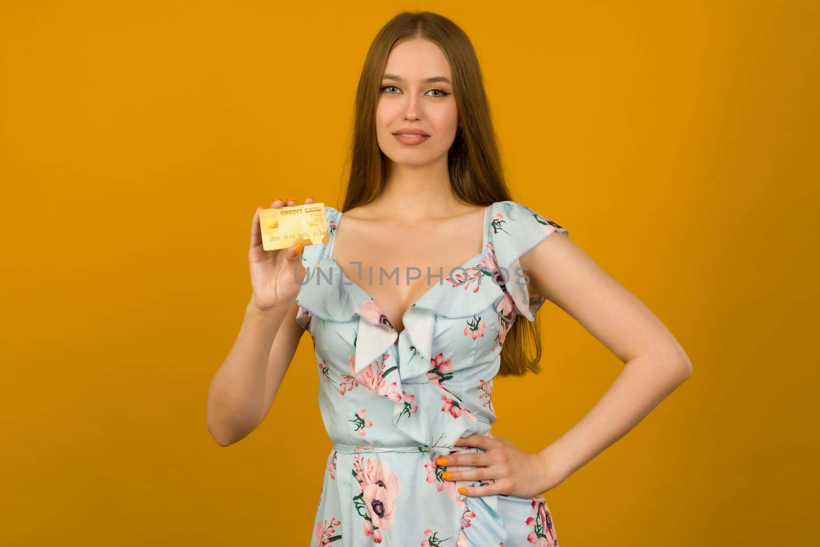 Photo of pleased young woman posing isolated over yellow wall background holding debit card. by zartarn