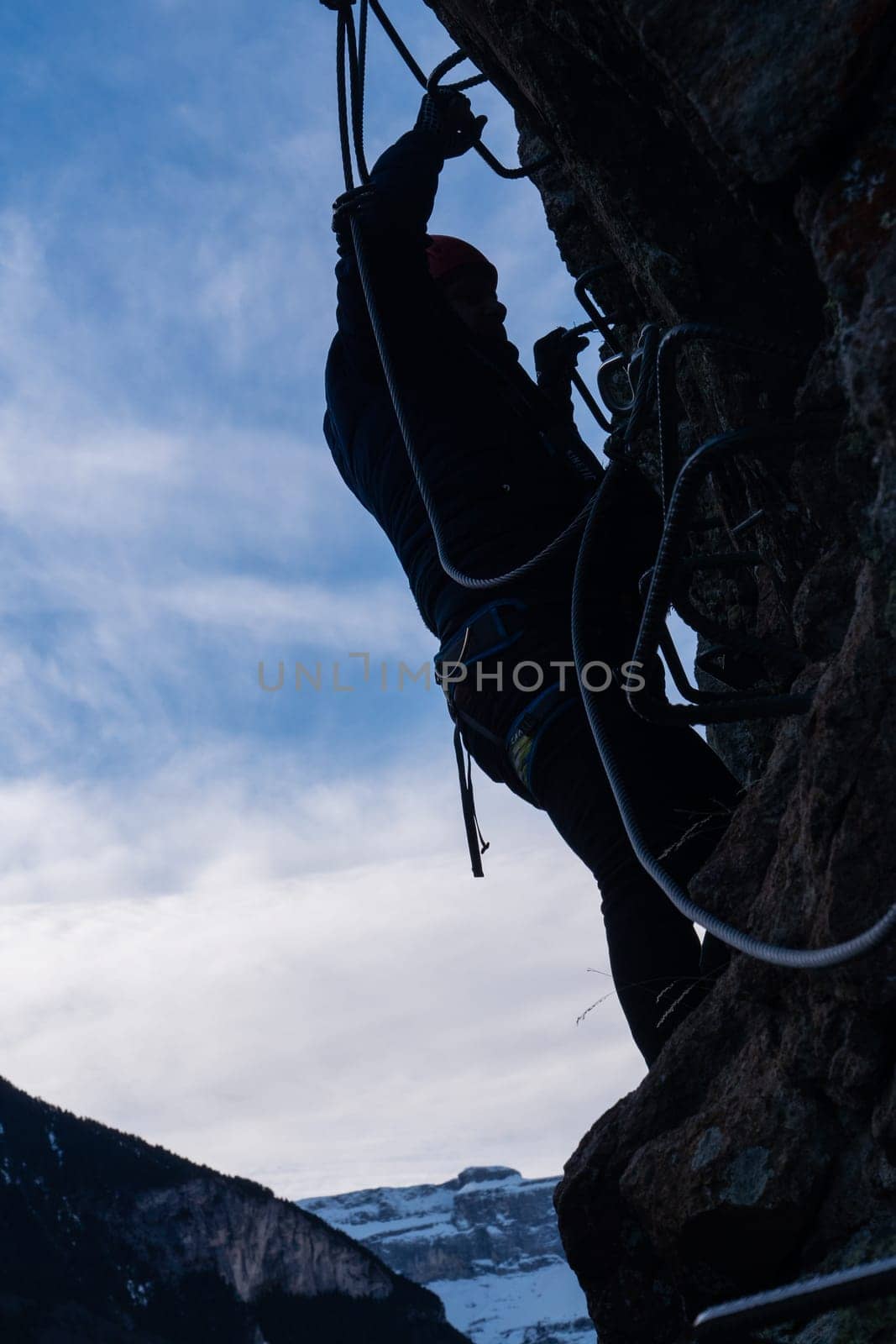 Man in body harnesses feature life-safety, attaches hooks to iron brackets, climbs rock, active lifestyle of people, mountaineering, viaferrata in mountains of pyrenees, High quality photo