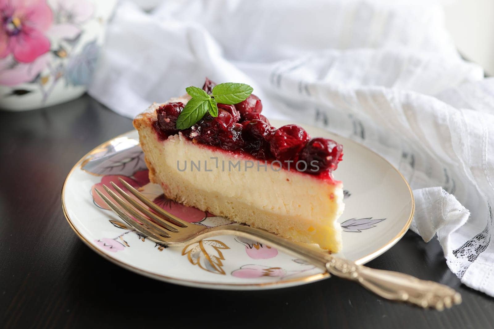 Appetizing portioned piece of cottage cheese tart and cherries on a porcelain plate. Tea party, morning, five o'clock.