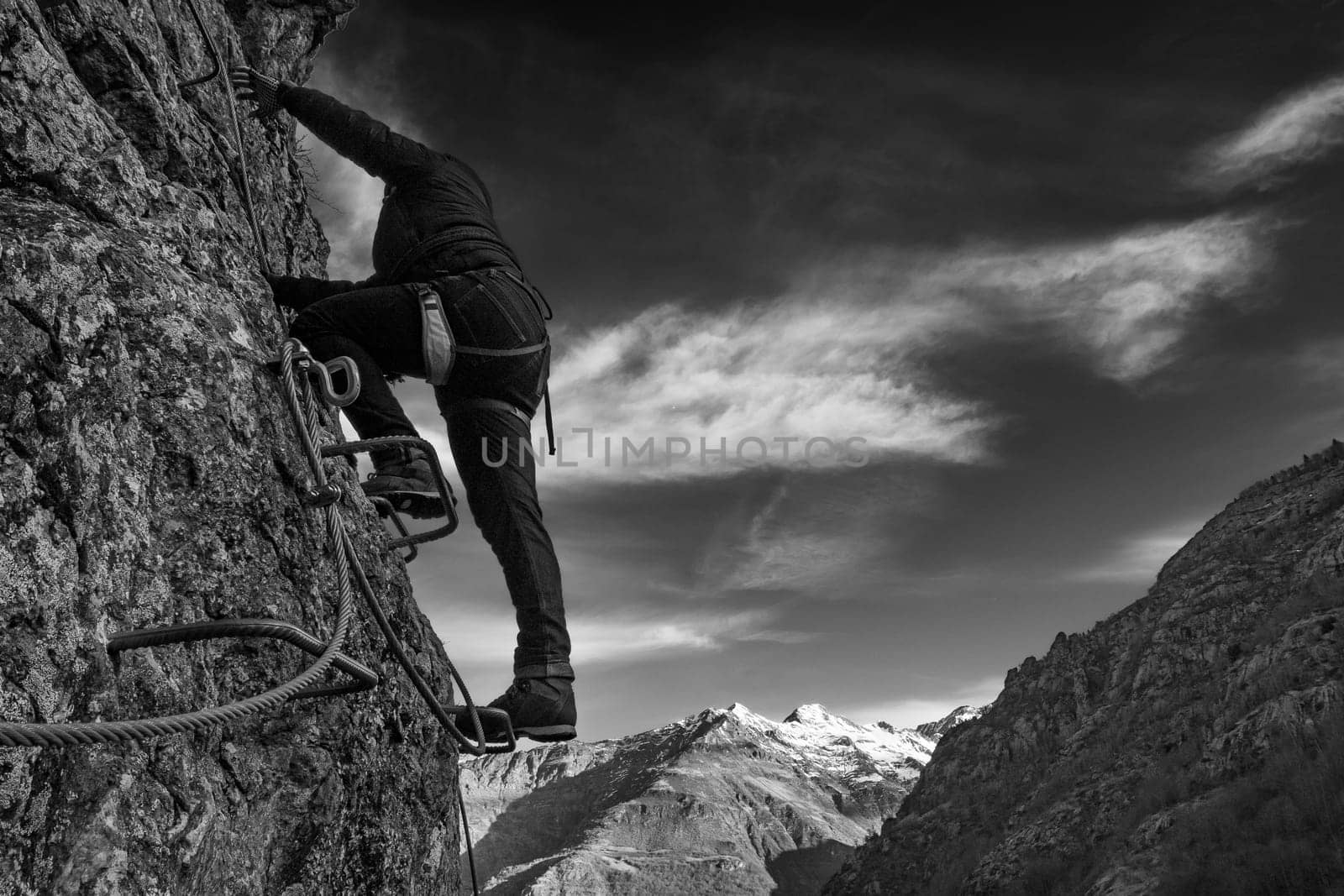 Man in body harnesses feature life-safety, attaches hooks to iron brackets, climbs rock, active lifestyle of people, mountaineering, viaferrata in mountains of pyrenees, High quality photo