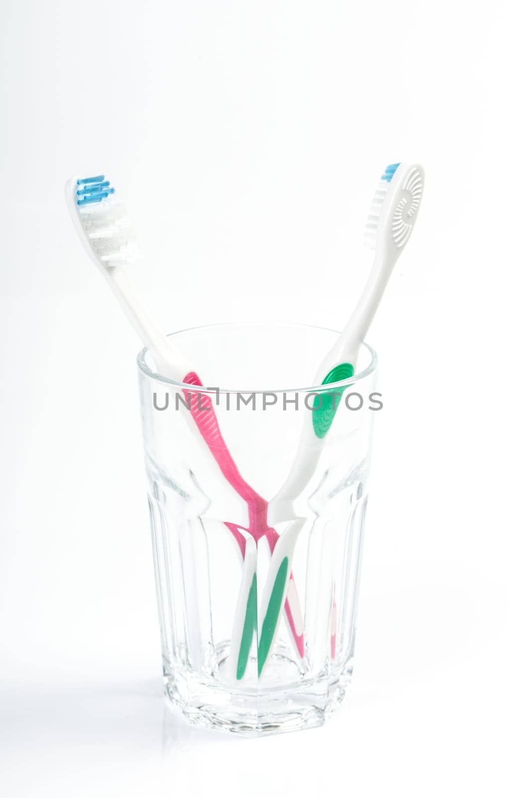 Toothbrushes in glass on table on light background by Fabrikasimf