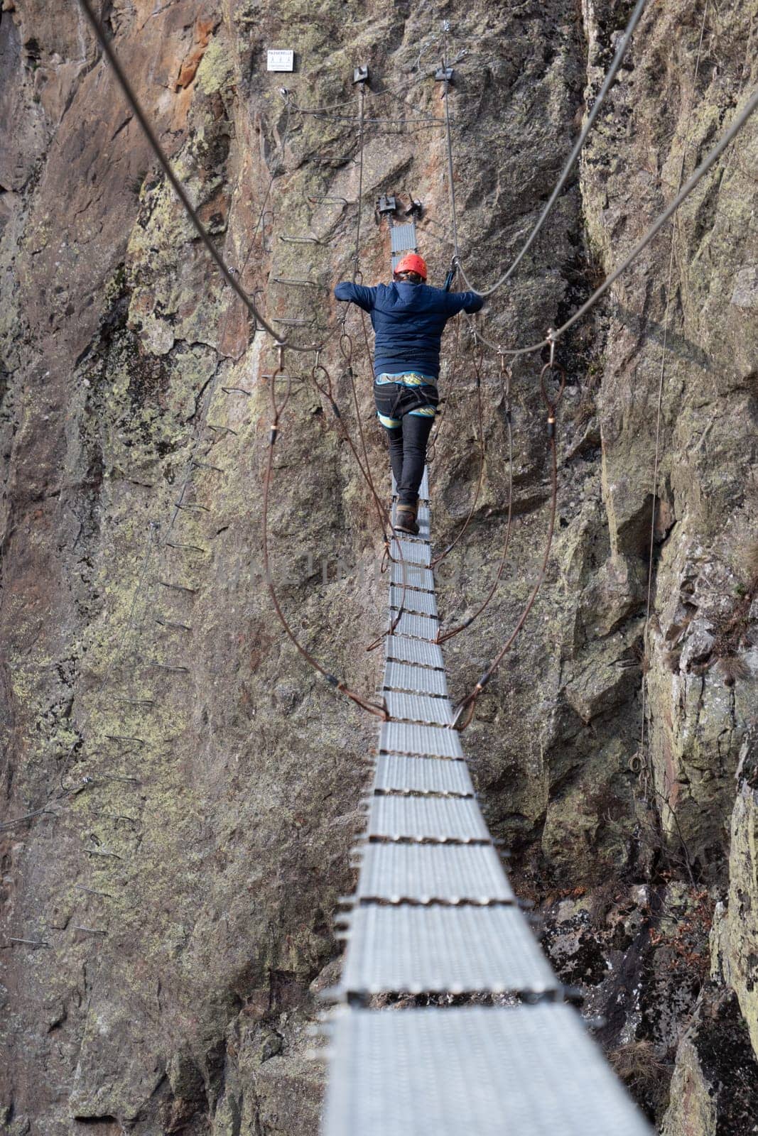 Man in body harnesses feature life-safety, attaches hooks to iron brackets, climbs rock, active lifestyle of people, mountaineering, viaferrata in mountains of pyrenees, High quality photo