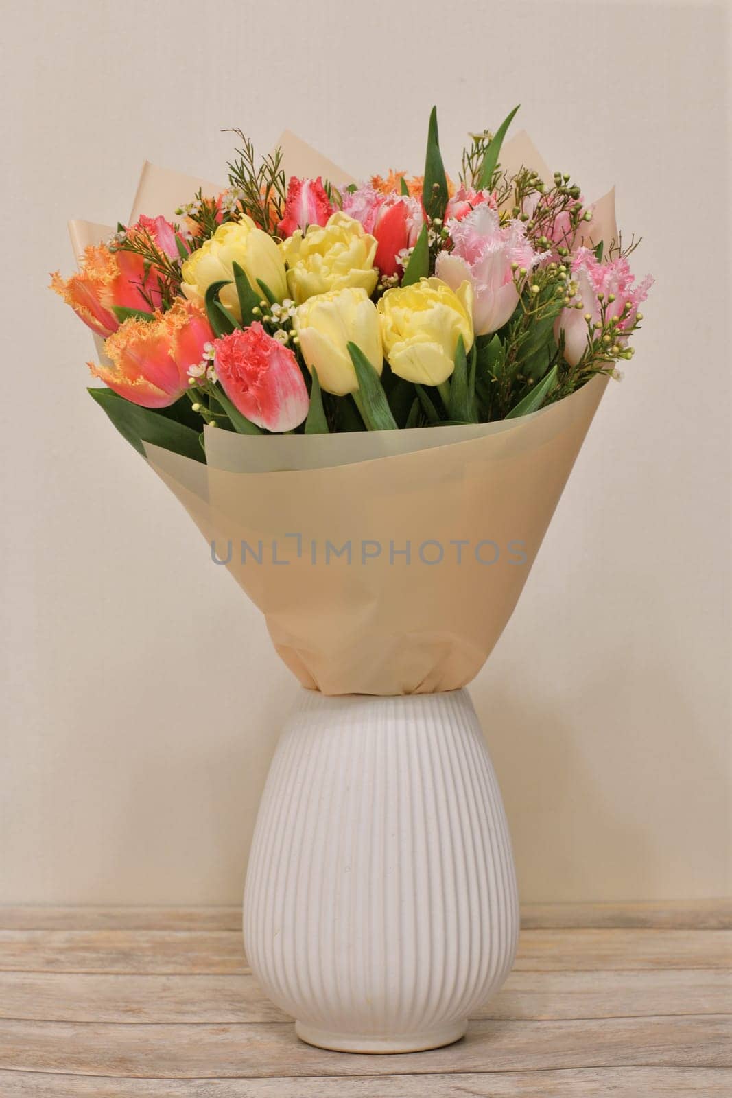 A bouquet of flowers in ceramic vase stands on a table in the room by olgavolodina