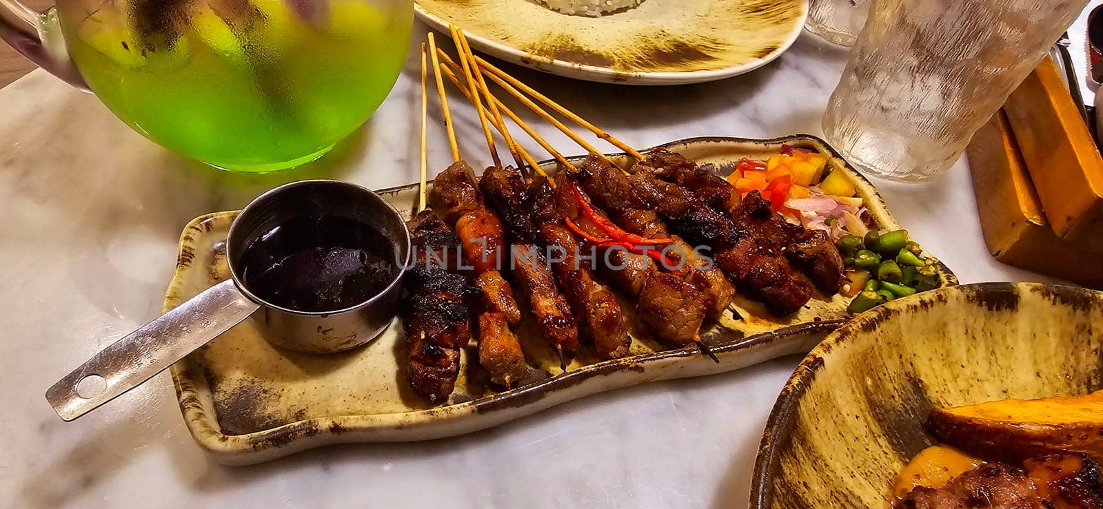 Homemade beef Satay marinated with spice and sweet soy sauce, coriander beef satay, served on plate with onion, chilli, soy sauce and tomato. Indonesian traditional food