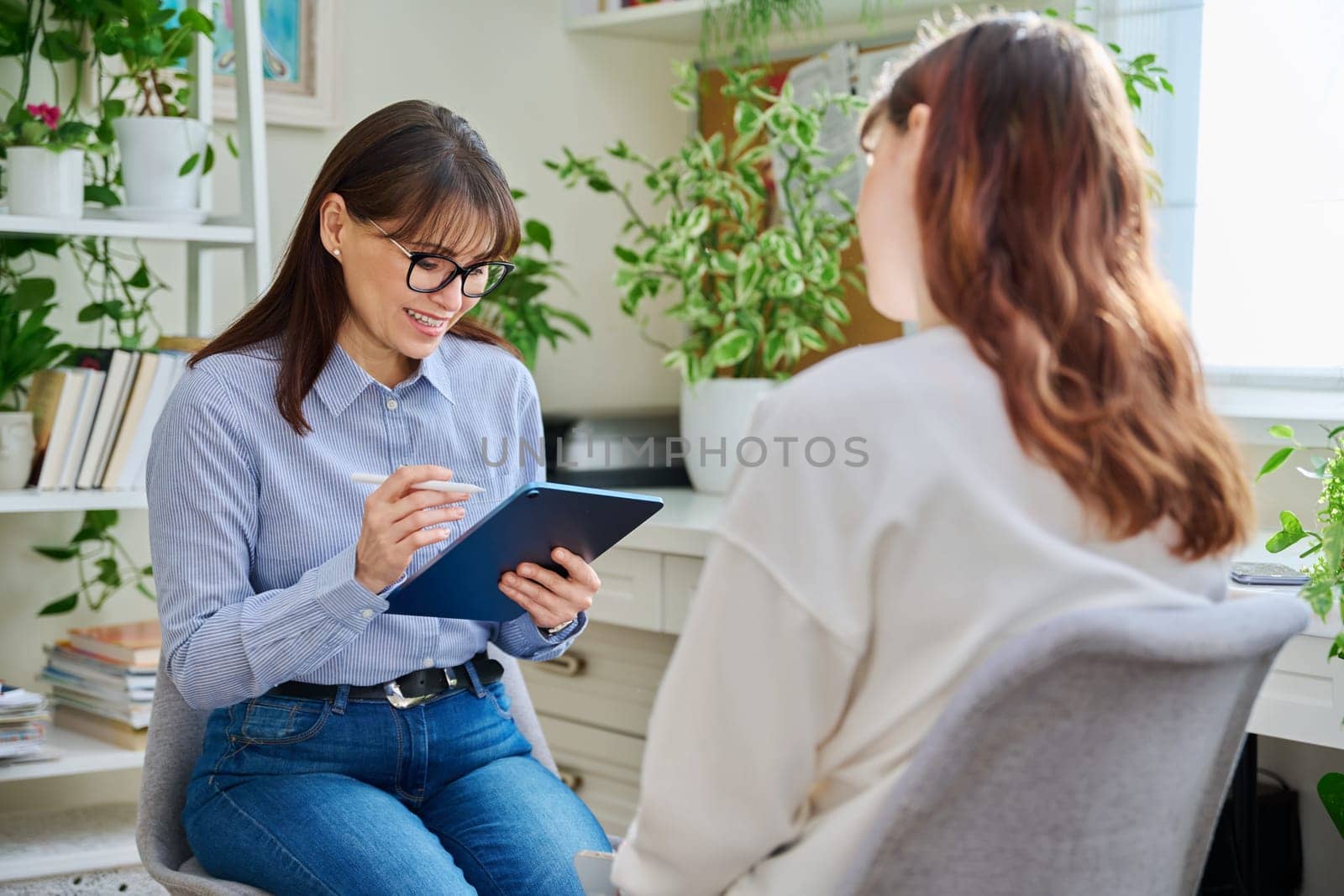 Professional mental therapist working with young woman, sitting together in office by VH-studio
