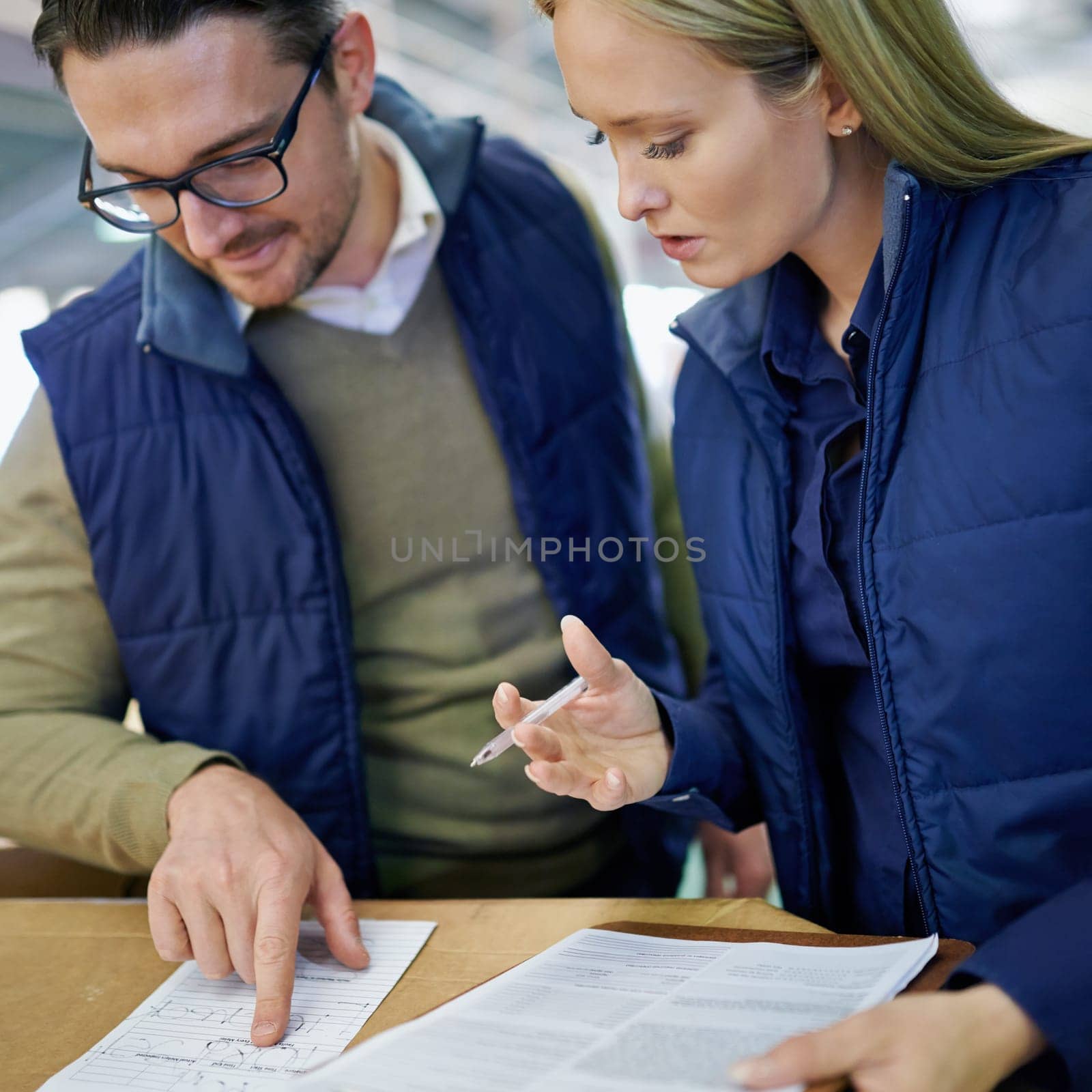 Business people, reading and pointing with checklist for inventory, storage or supply chain at warehouse. Happy coworkers, team or employees looking at documents, paperwork or distribution at factory.