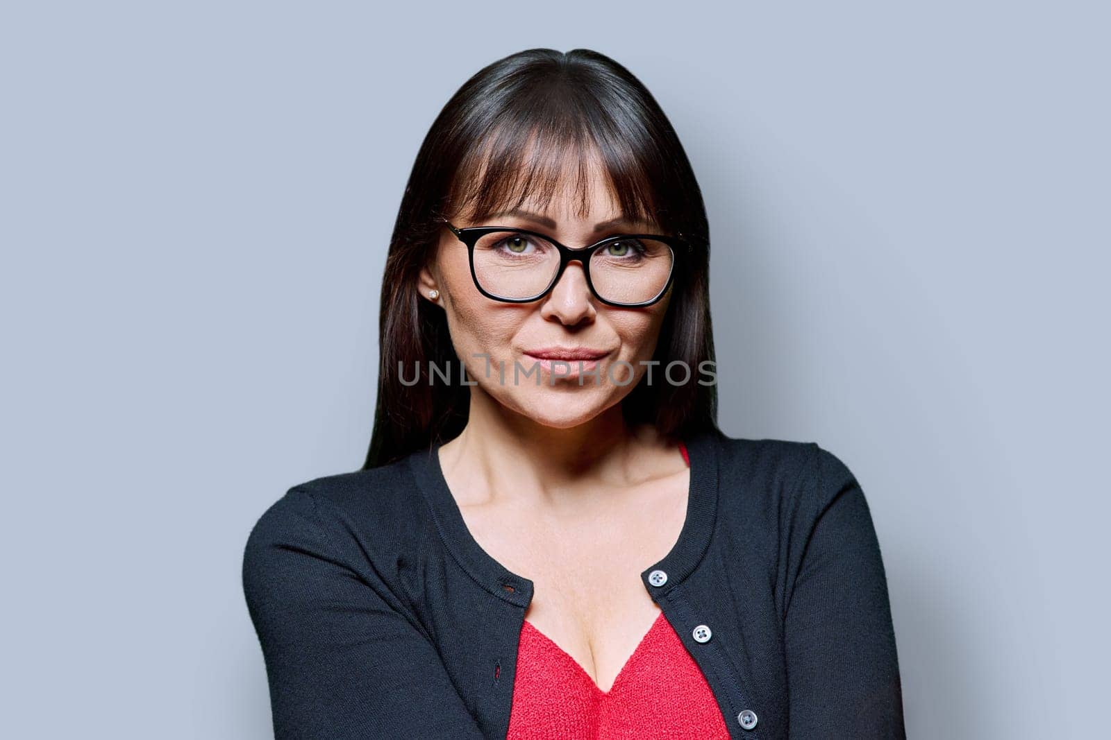 Headshot portrait of serious confident business mature woman on grey studio background. Successful elegant attractive middle-aged female looking at camera. Business, work, job, lifestyle, 40s people