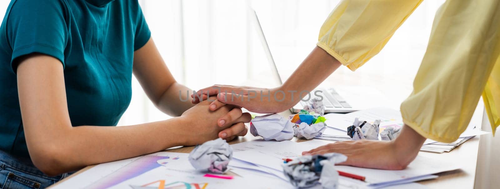 Panorama startup employee holding hand to stressed colleague due to failure, frustrated from no inspiration, lack of idea. Exhausted from overwhelm work and supportive coworker concept. Synergic