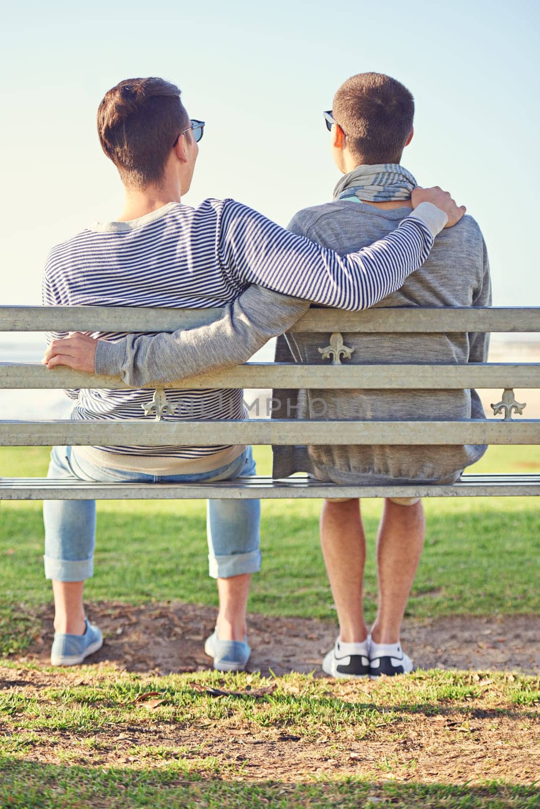 Couple, gay and men for hugging with park bench, nature and honeymoon at beach. Male tourists, sunlight and summer vacation for romance with partner, relaxing and travel on grass in Cape Town by YuriArcurs