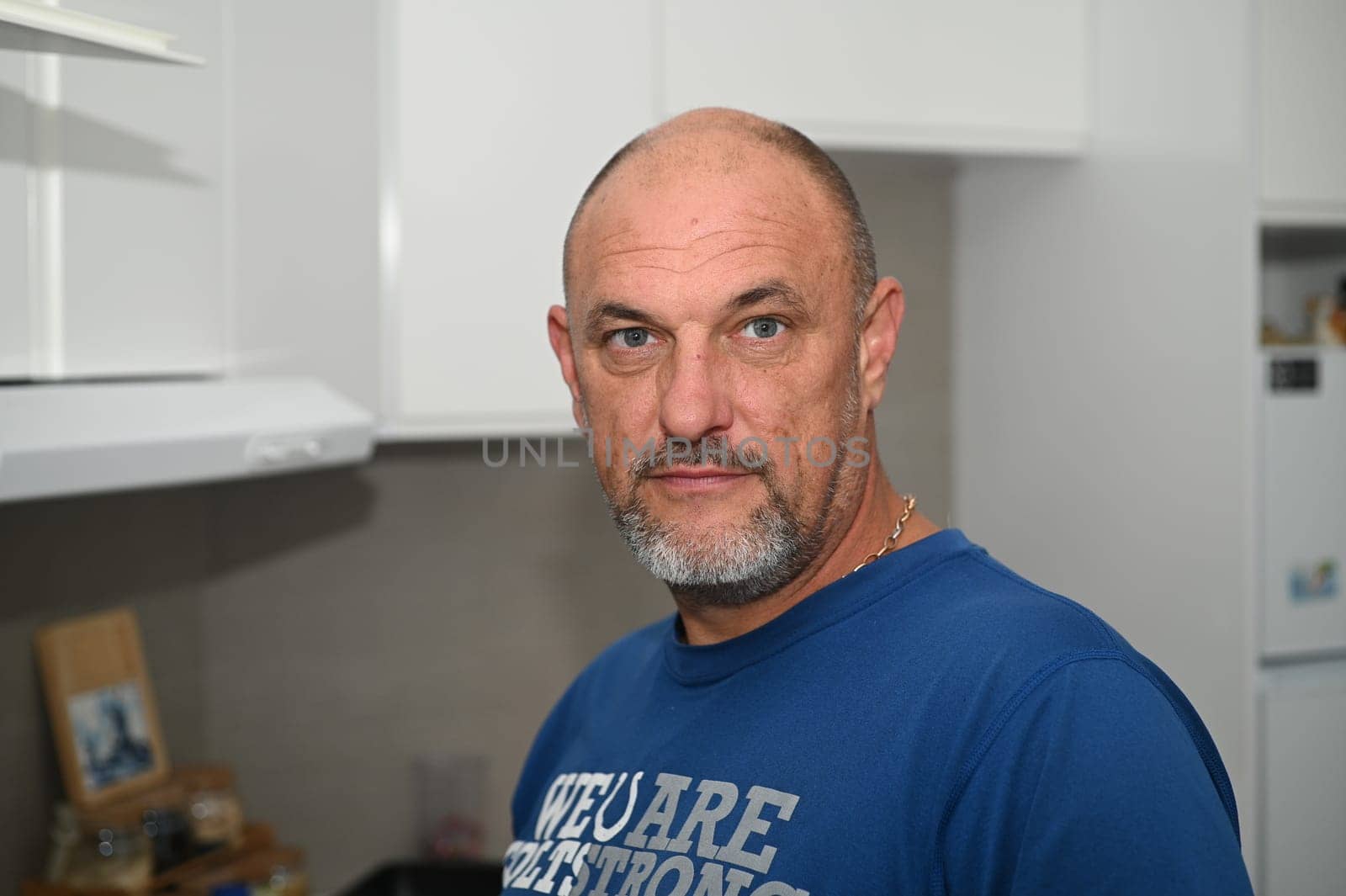 man with gray eyes in a blue T-shirt in a white kitchen 2