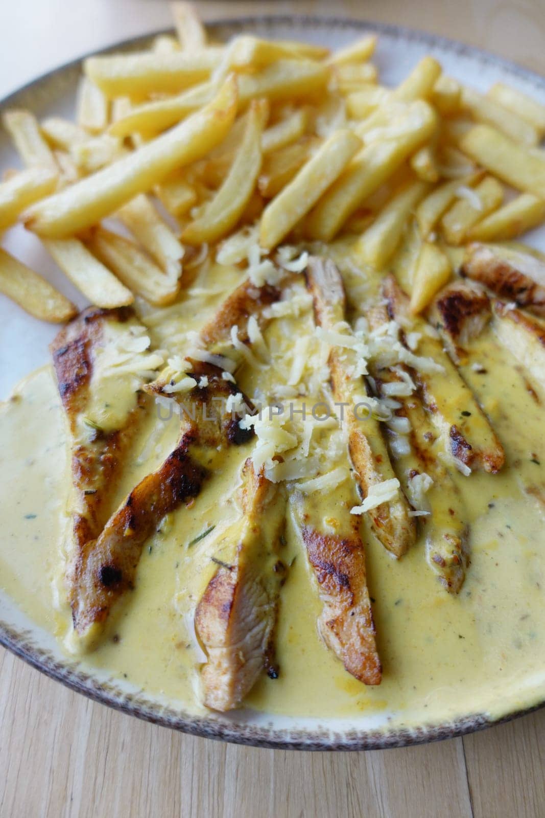 Ready to eat sliced chicken with cream sauce with french fries on a plate . by towfiq007