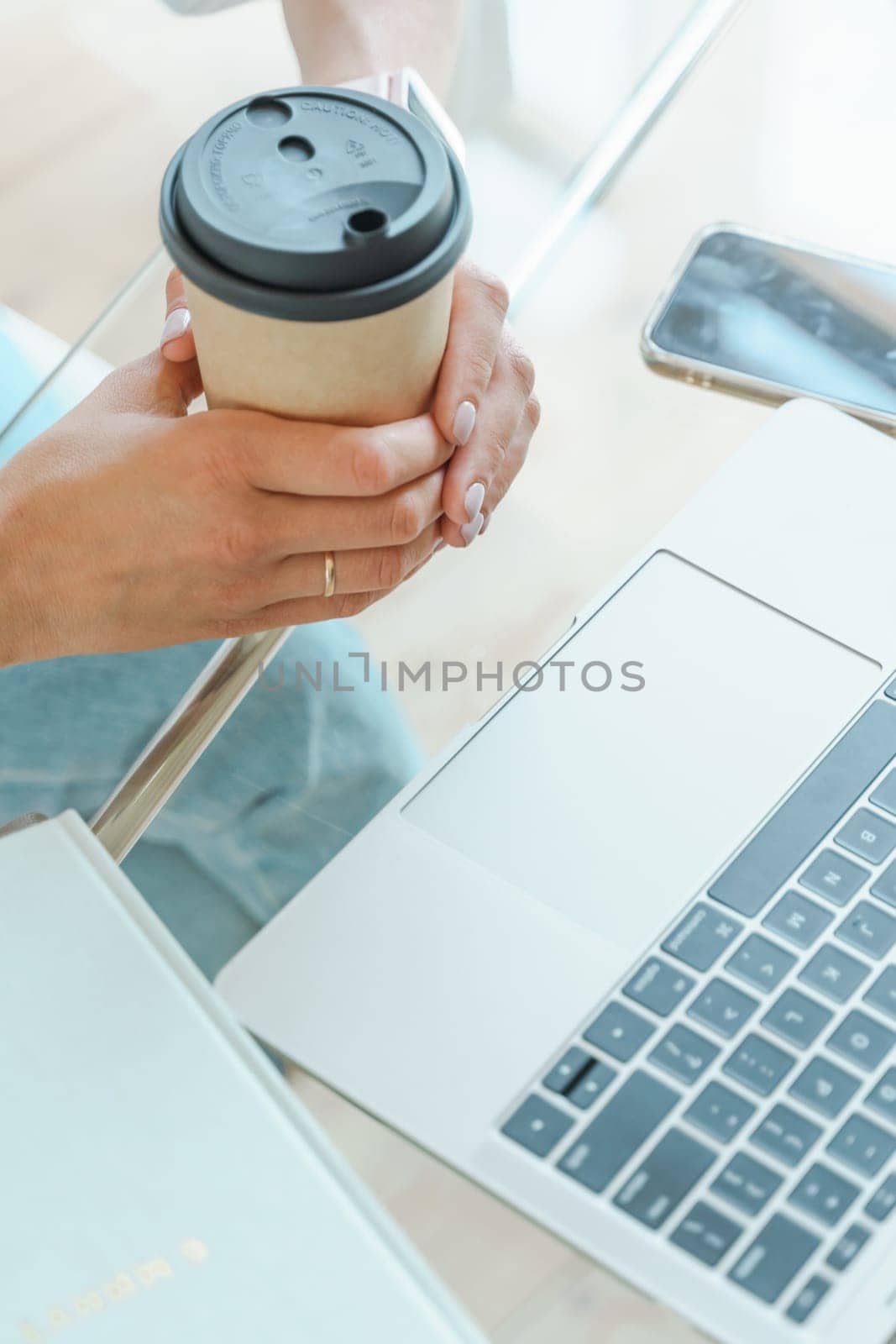 Hands typing on a computer keyboard over a white office table with a cup of coffee and supplies, top view