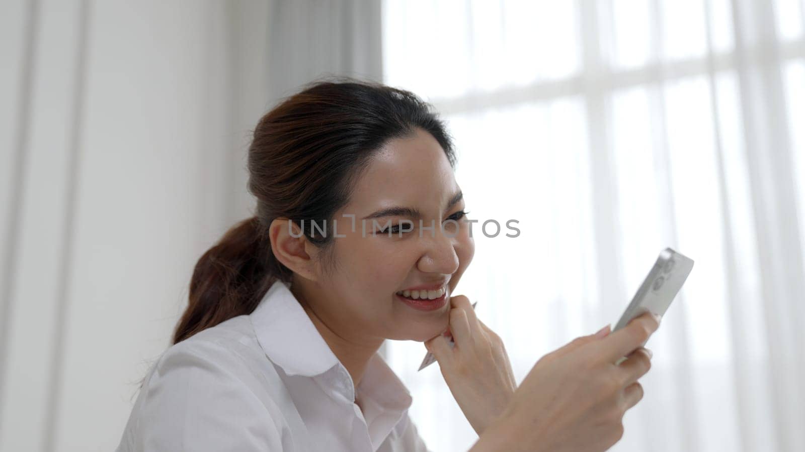 Young woman using smartphone browsing for online shopping E commerce by online payment gateway at vivancy home. Modern and convenience online purchasing make secure and convenient purchases.