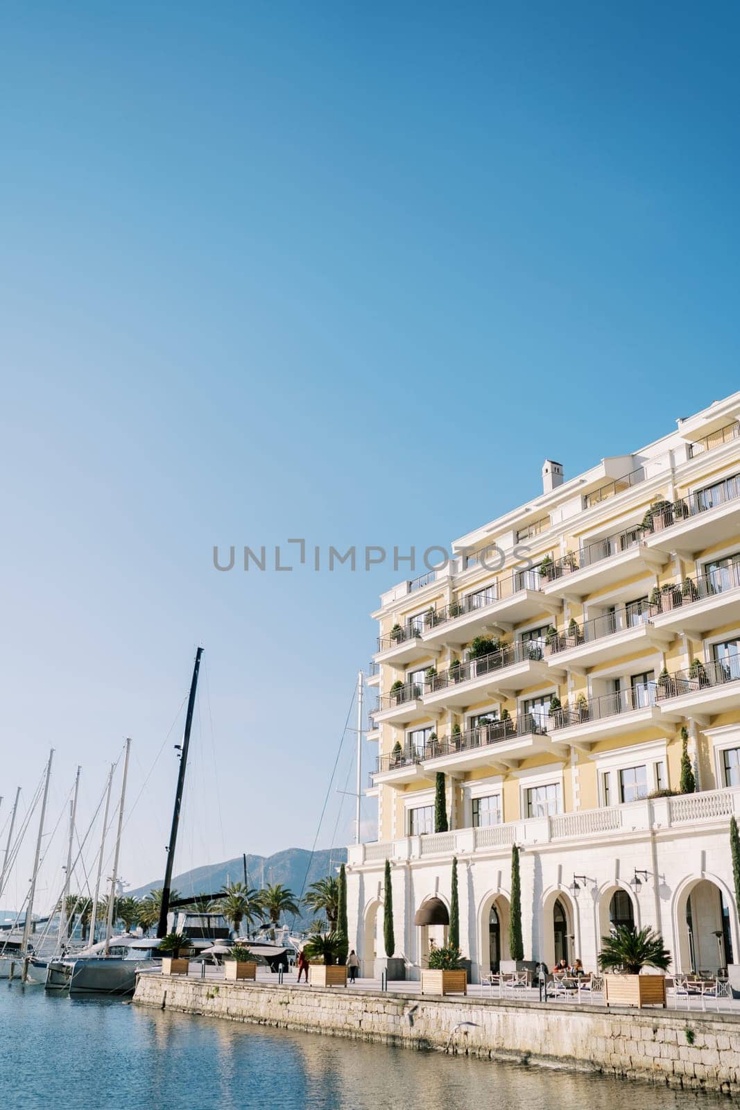 Luxurious Regent Hotel on the seafront next to moored sailing yachts. Porto, Montenegro by Nadtochiy