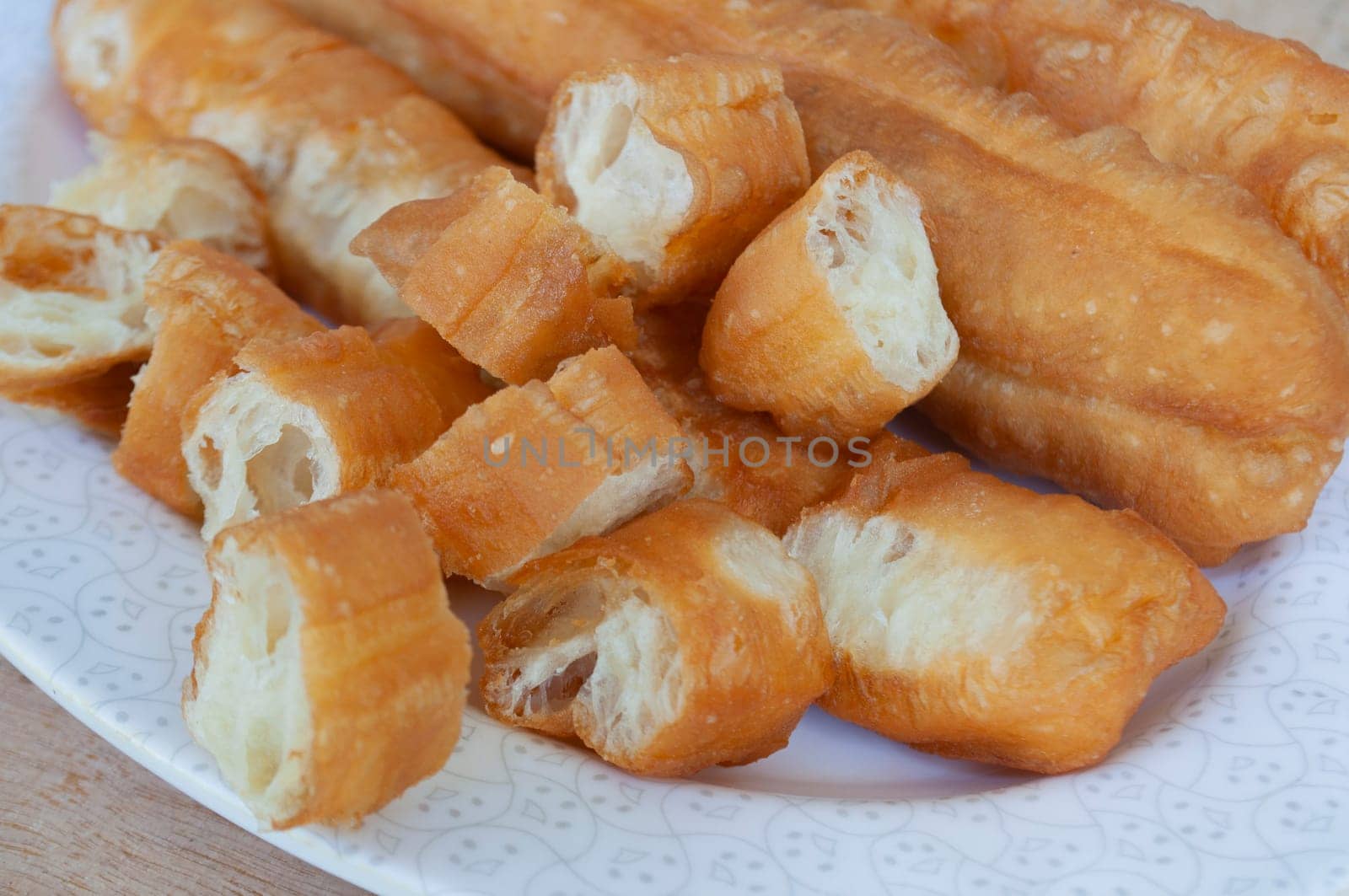 Close up view of cut cakoi or youtiao cake on white plate. Asian food concept.