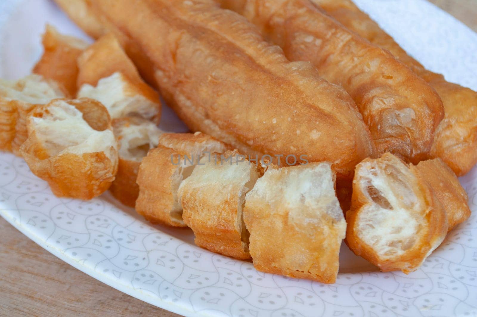 Close up of cut cakoi or Youtiao on white plate. Asian food concept.
