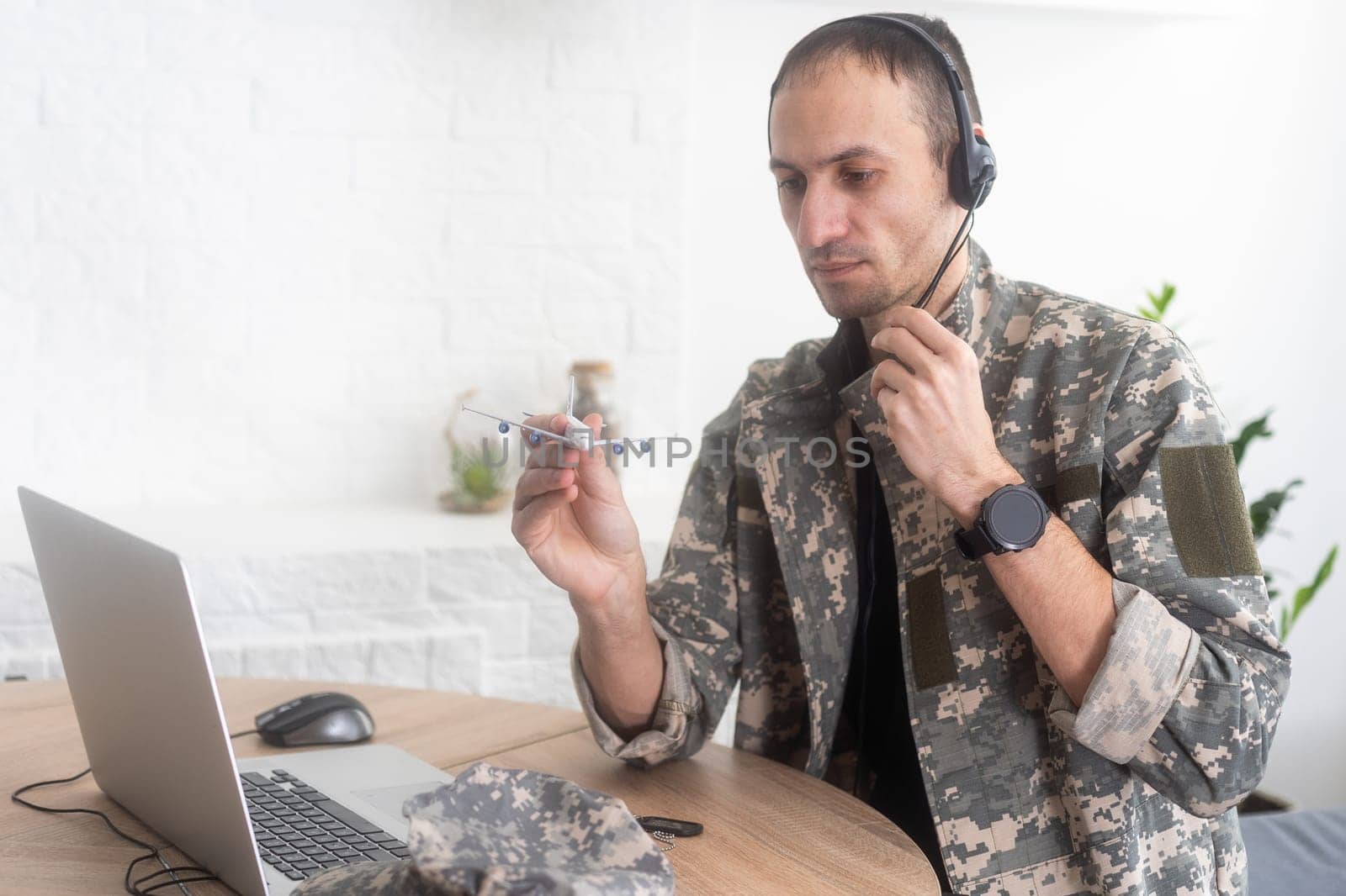 Military Technical Service, Air Force Concept. Hands of a man in uniform holding a silver toy airplane. A middle-aged adult man in a green camouflage uniform. Indoors. High quality photo
