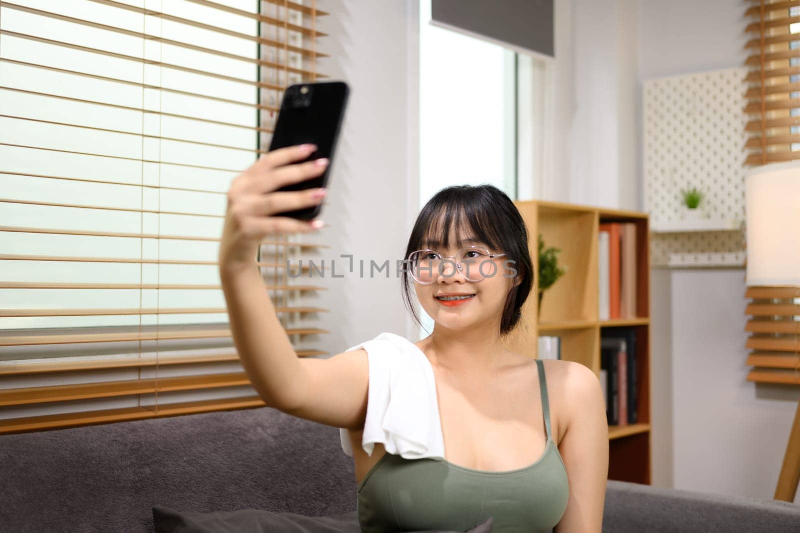 Cute young woman taking selfie with smartphone after finishing home workout.