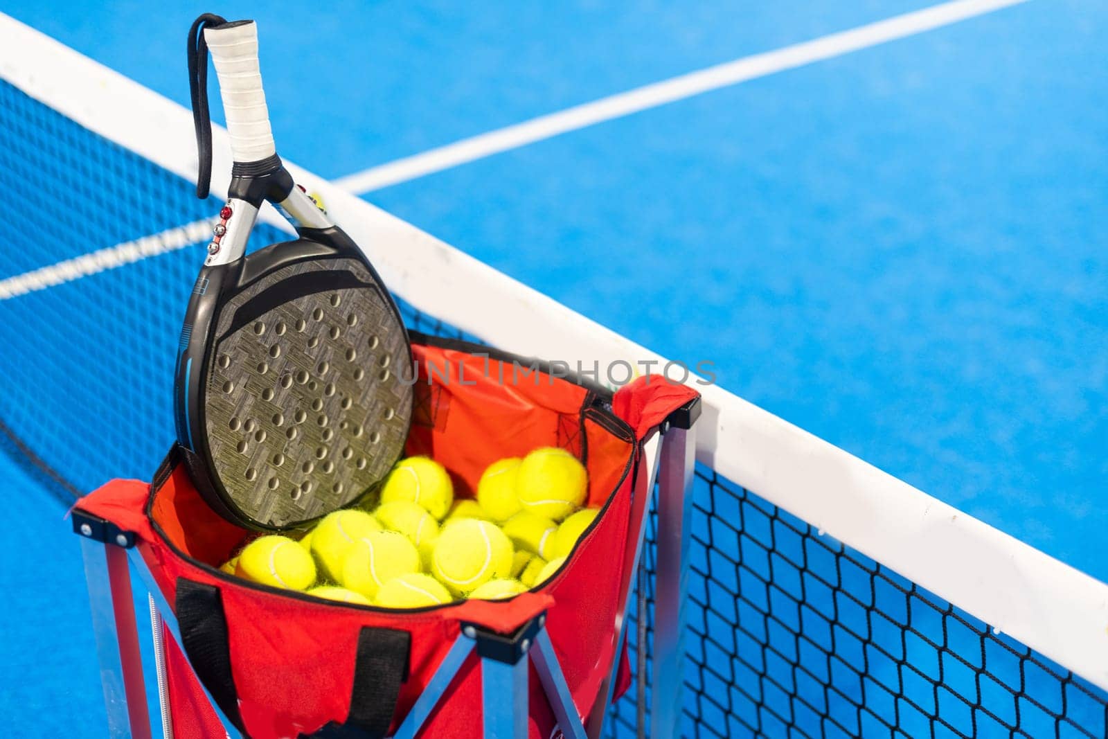 Paddle tennis rackets, balls and basket in court still life. High quality photo