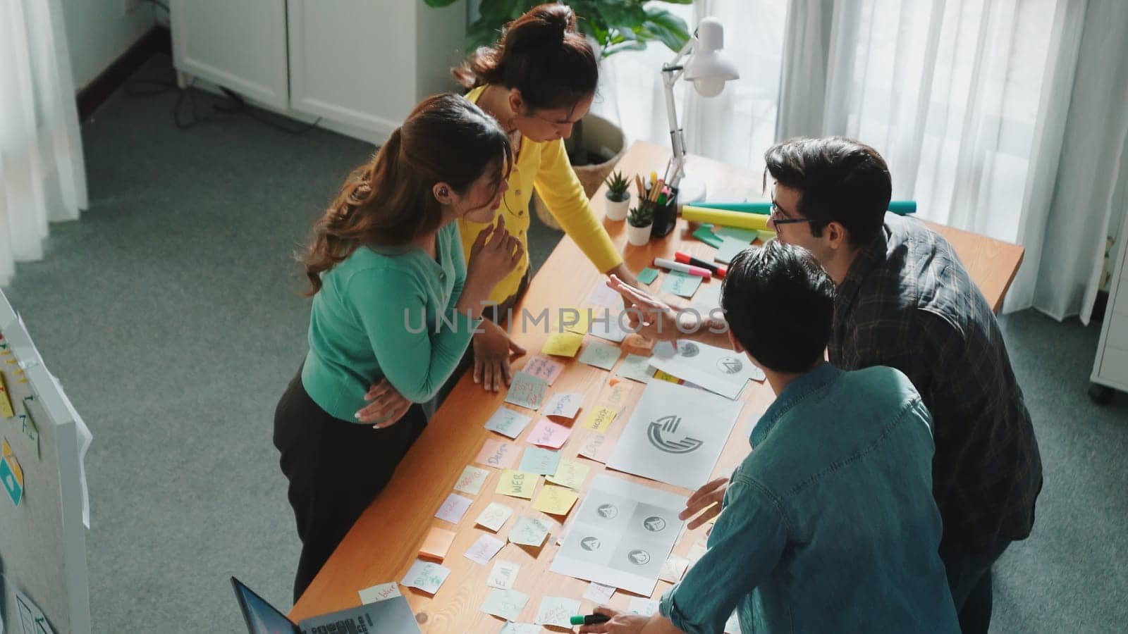 Top view of skilled designer explain and brainstorming idea for logo design and writing concept. Aerial view of business people discuss and talking while using sticky notes sharing idea. Symposium.