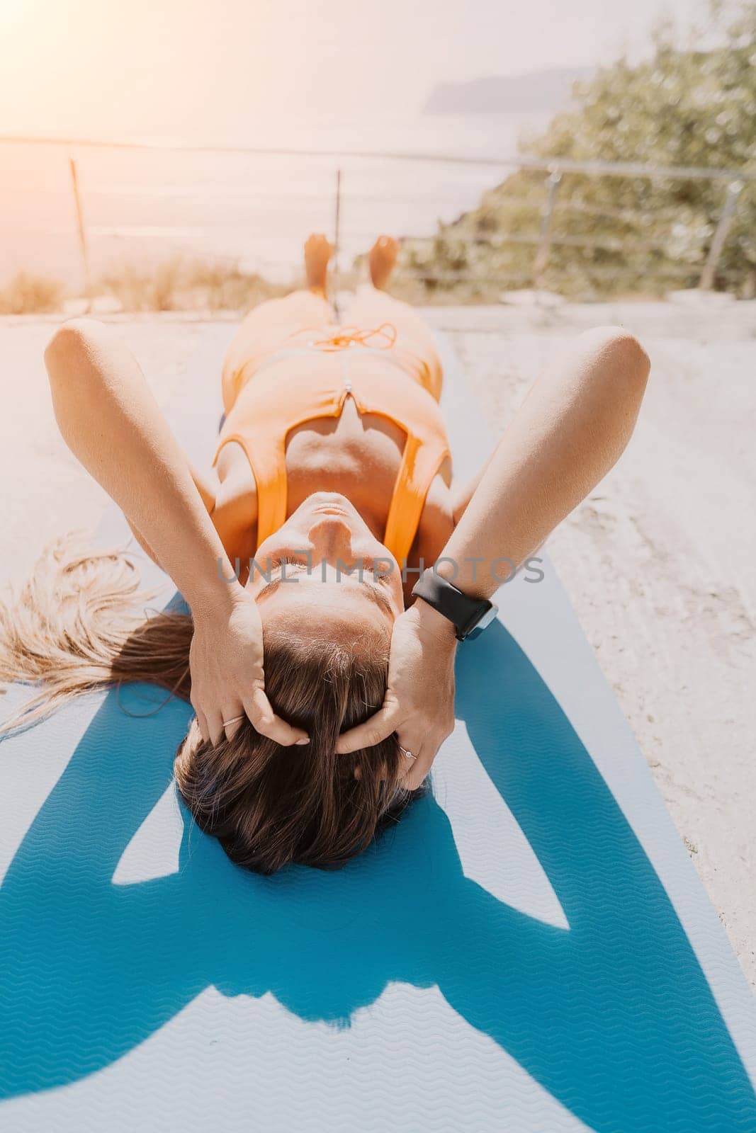 Fitness woman sea. Outdoor workout on yoga mat in park near to ocean beach. Female fitness pilates yoga routine concept. Healthy lifestyle. Happy fit woman exercising with rubber band in park.