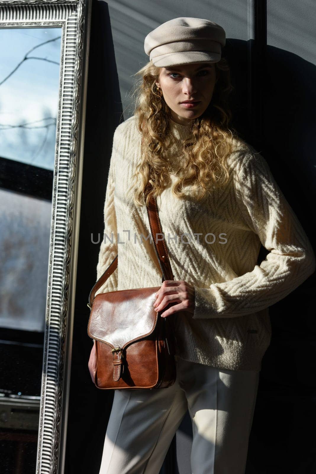 beautiful curly blond hair woman posing with a small brown Model wearing stylish cap white sweater and classic trousers