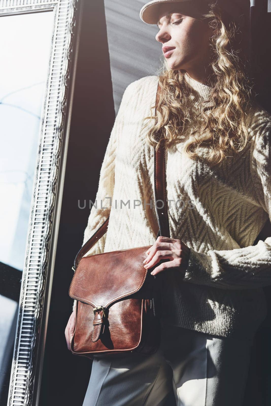 beautiful curly blond hair woman posing with a small brown Model wearing stylish cap white sweater and classic trousers