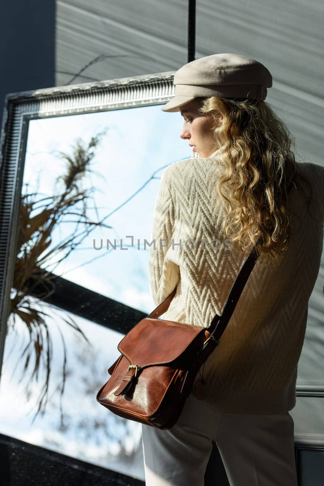 beautiful curly blond hair woman posing with a small brown Model wearing stylish cap white sweater and classic trousers