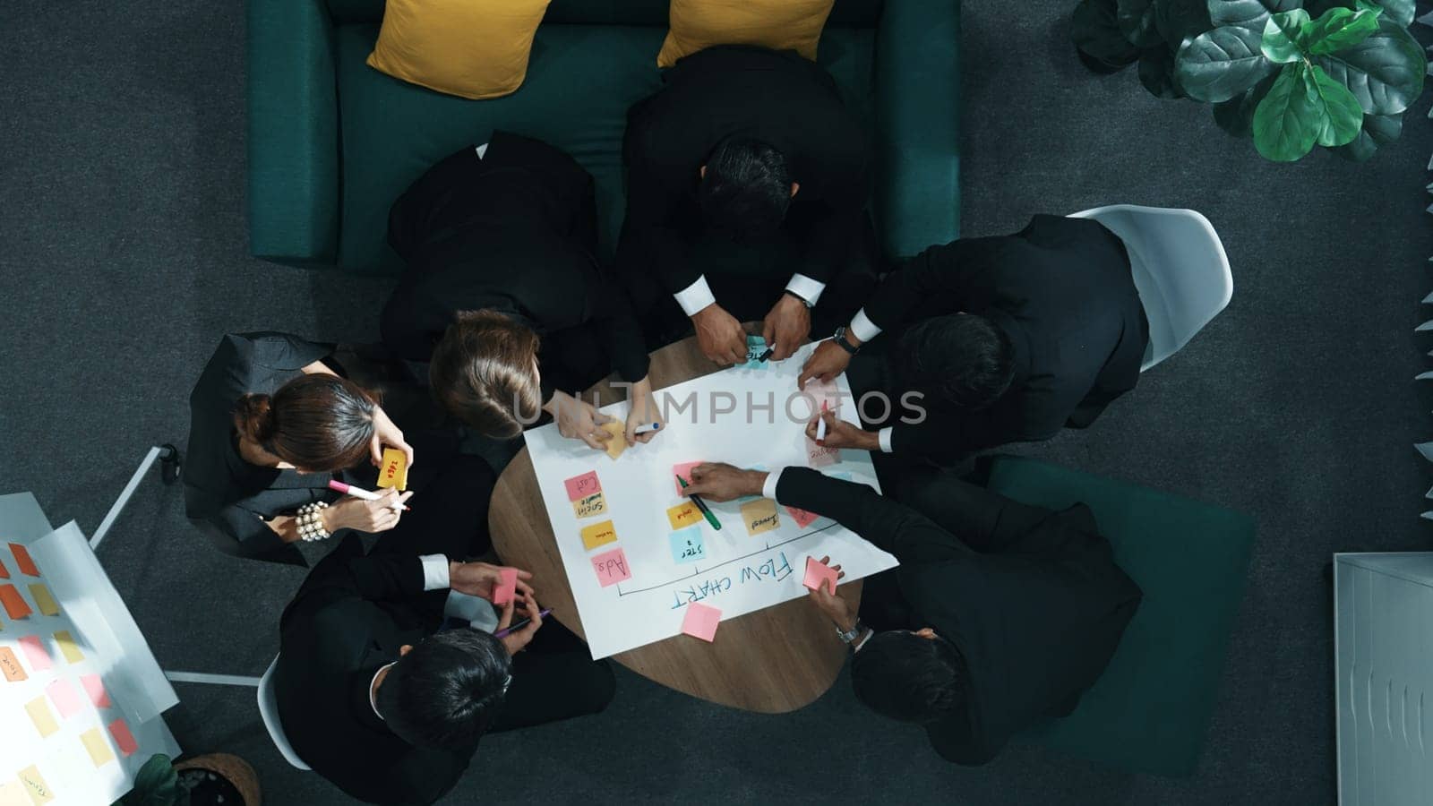 Close up of professional business team hands writing and putting sticky note on scrum task board. Top view of project manager write task and use kanban board to manage time and workflow. Directorate.