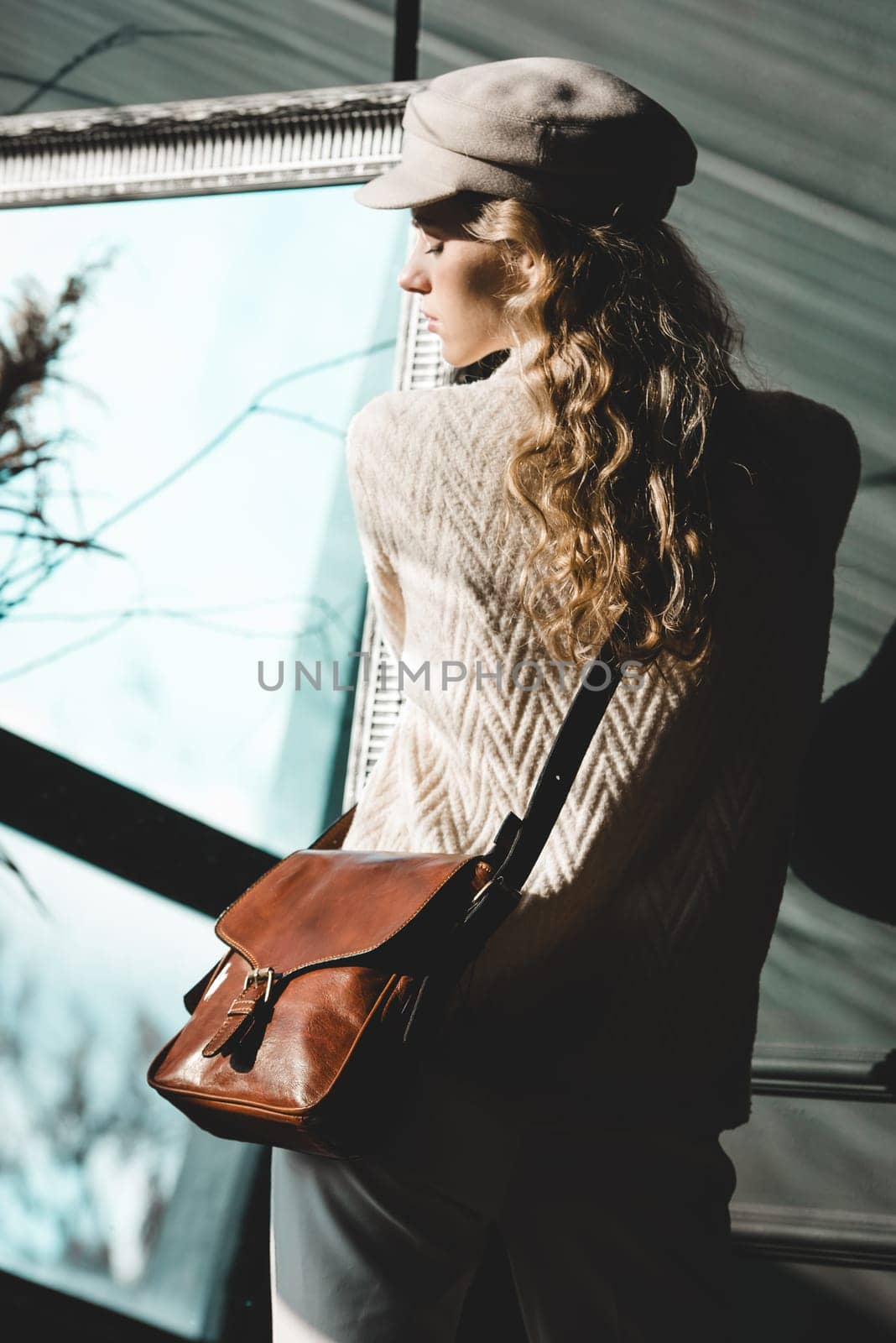 beautiful curly blond hair woman posing with a small brown Model wearing stylish cap white sweater and classic trousers