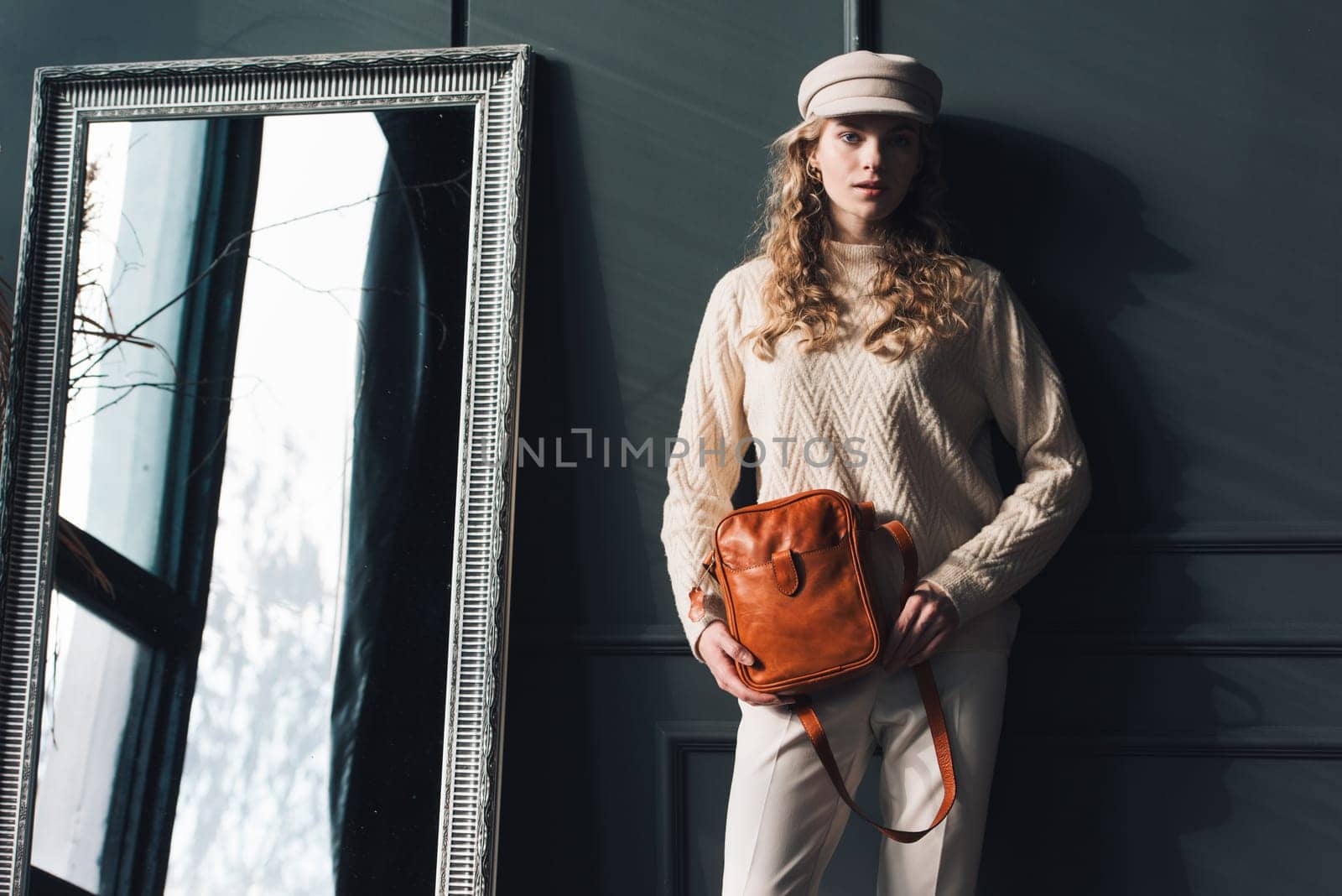 beautiful curly blond hair woman posing with a small brown Model wearing stylish cap white sweater and classic trousers