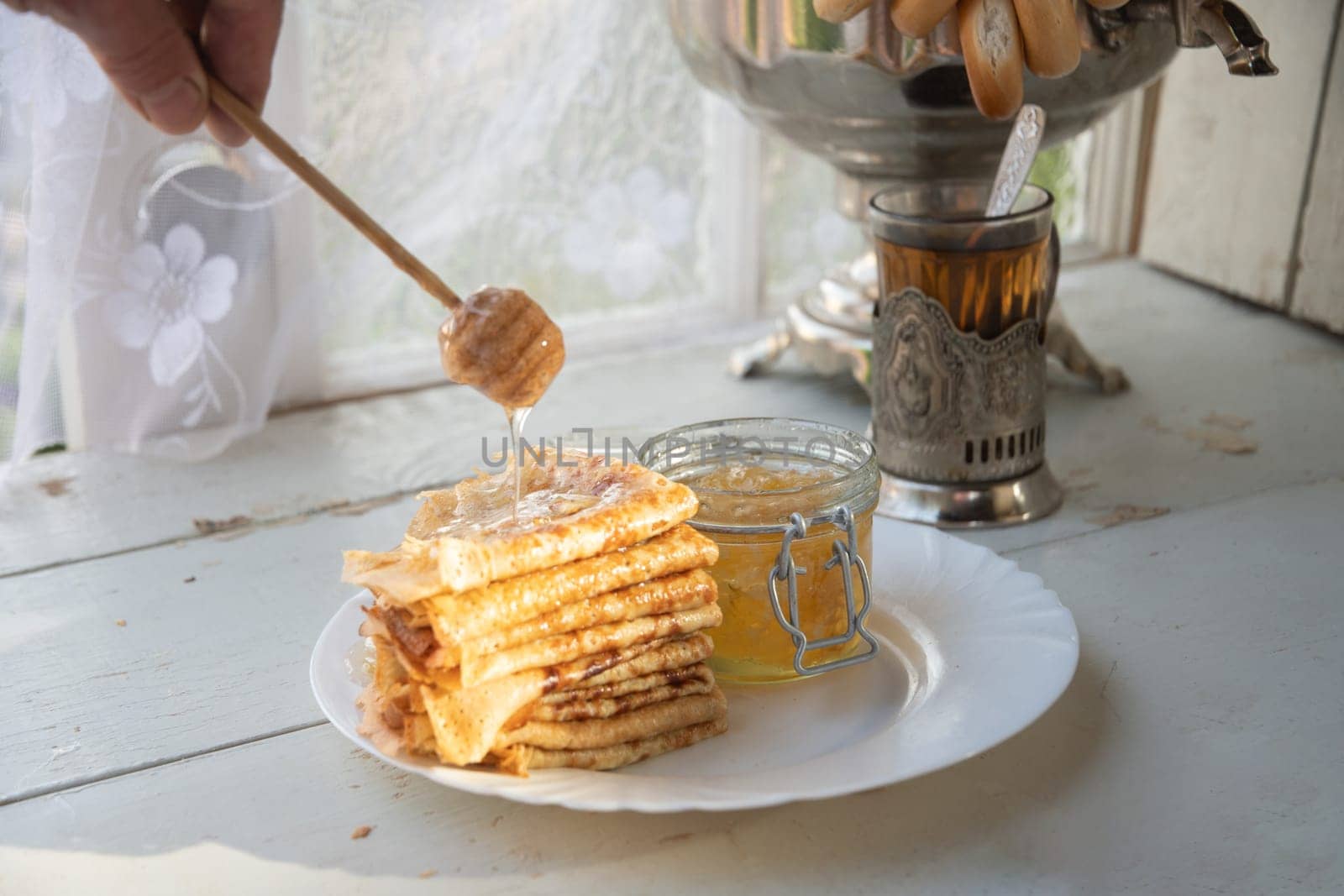 Russian pancakes with honey and a cup of tea from a vintage samovar Maslenitsa festival concept by KaterinaDalemans