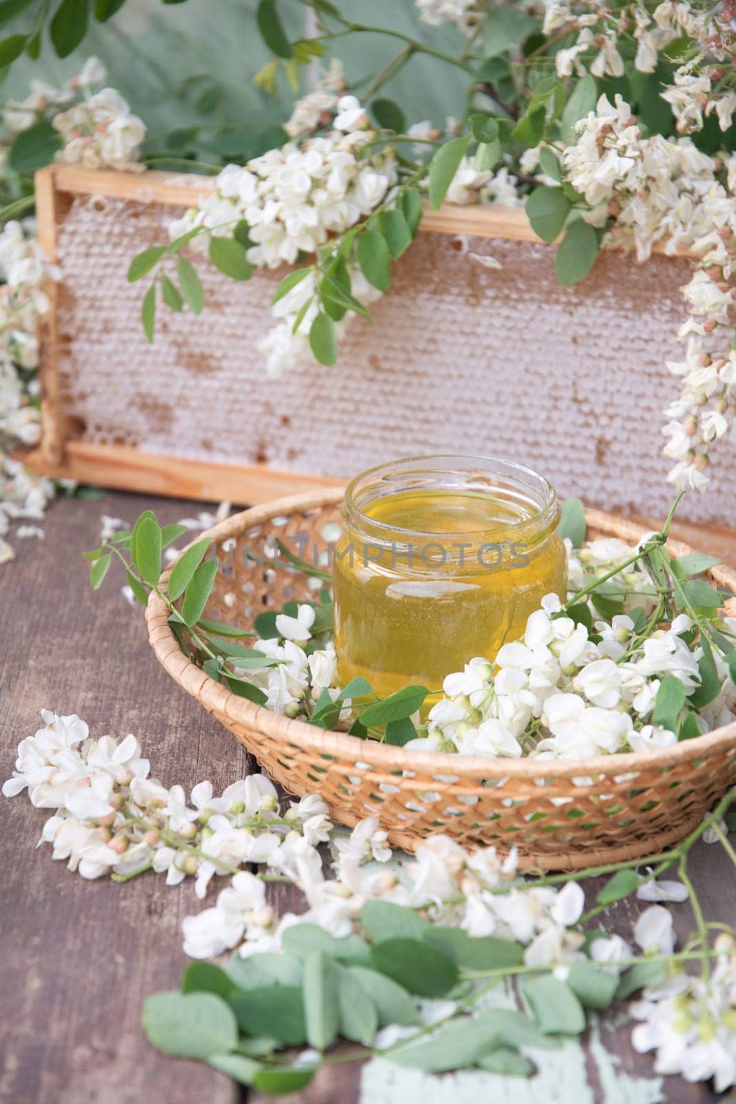 still life of a full jar of transparent yellow ocacia honey on the table against the background of wax honeycombs, organic enriched beekeeping product for alternative medicine, high quality photo