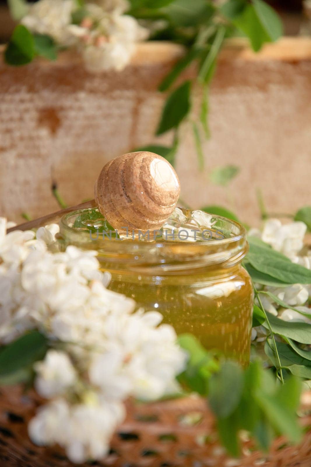 still life of a full jar of transparent yellow ocacia honey on the table against the background of wax honeycombs, organic enriched beekeeping product for alternative medicine, high quality photo