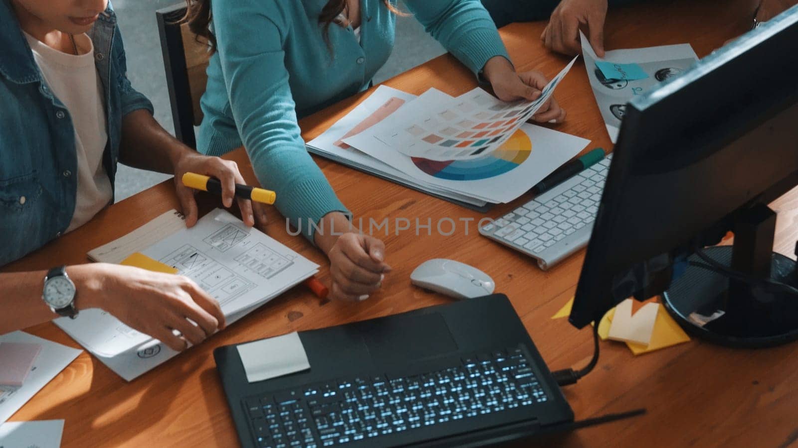 Top down view of smart designer helping manager choosing color from colored palettes. Aerial view of businessman working together and planning together while looking at logo from laptop. Symposium.