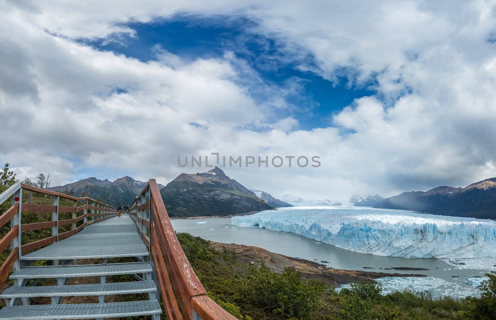 Glacier seen from walkway under vibrant clouds.
