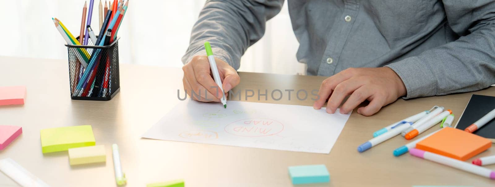 Skilled businessman brainstorms marketing ideas using mind maps. Successful male startup leader drafts financial plan on table with sticky notes scatter around. Closeup. Focus on hand.Variegated.