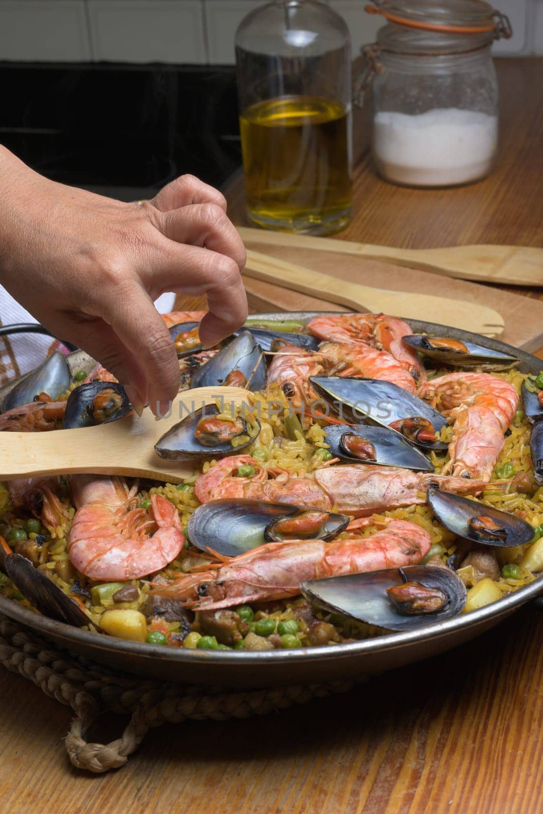 Cooking paella with shrimp and mussels using a wooden utensil in a home kitchen, typical Spanish cuisine, Majorca, Balearic Islands, Spain,