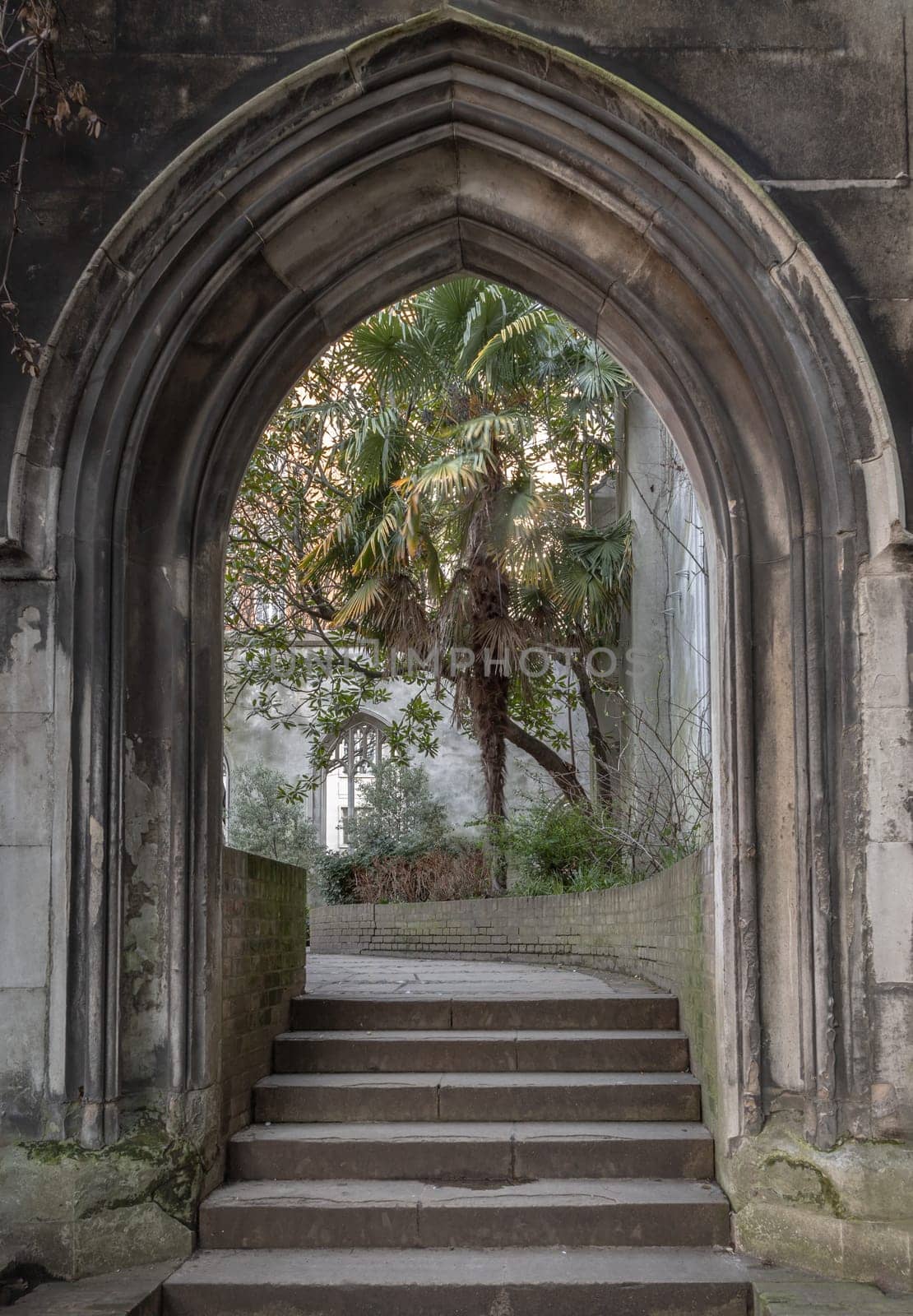 London, UK - Feb 27, 2024 - The stone arched entrance leads to the stone staircase inside of St Dunstan in the East Church Garden. The historic church was bombed and destroyed in the Second World War and is now a park, London city hidden places, Copy space, Selective focus.