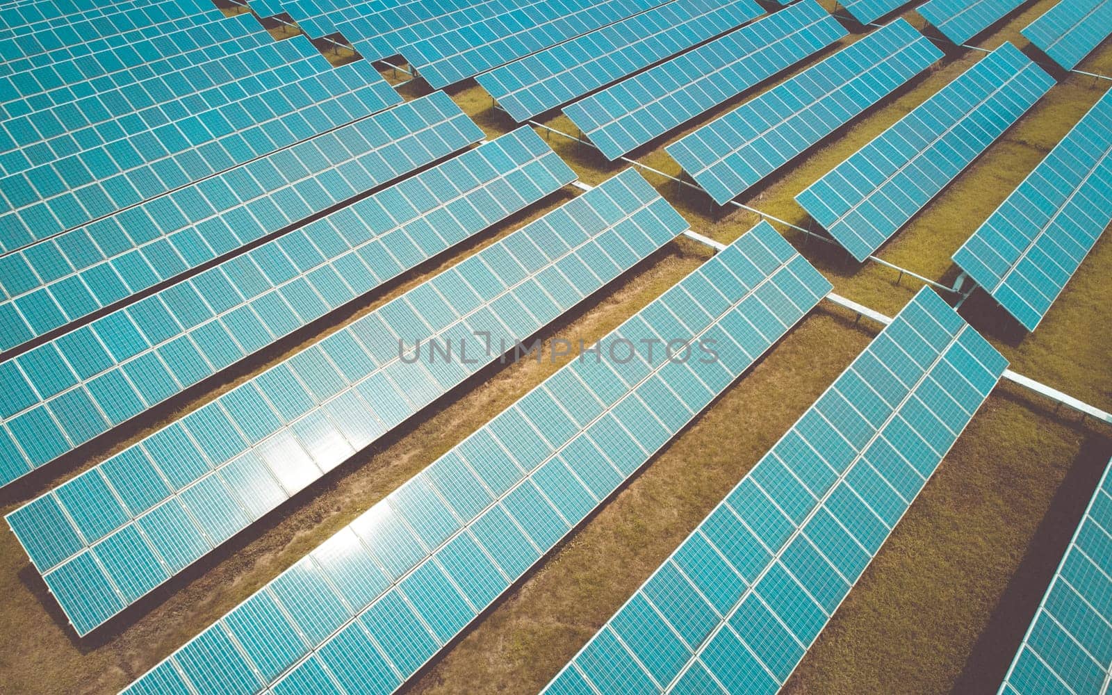 Aerial shot of solar panels farm on the green field. Renewable alternative green energy concept.