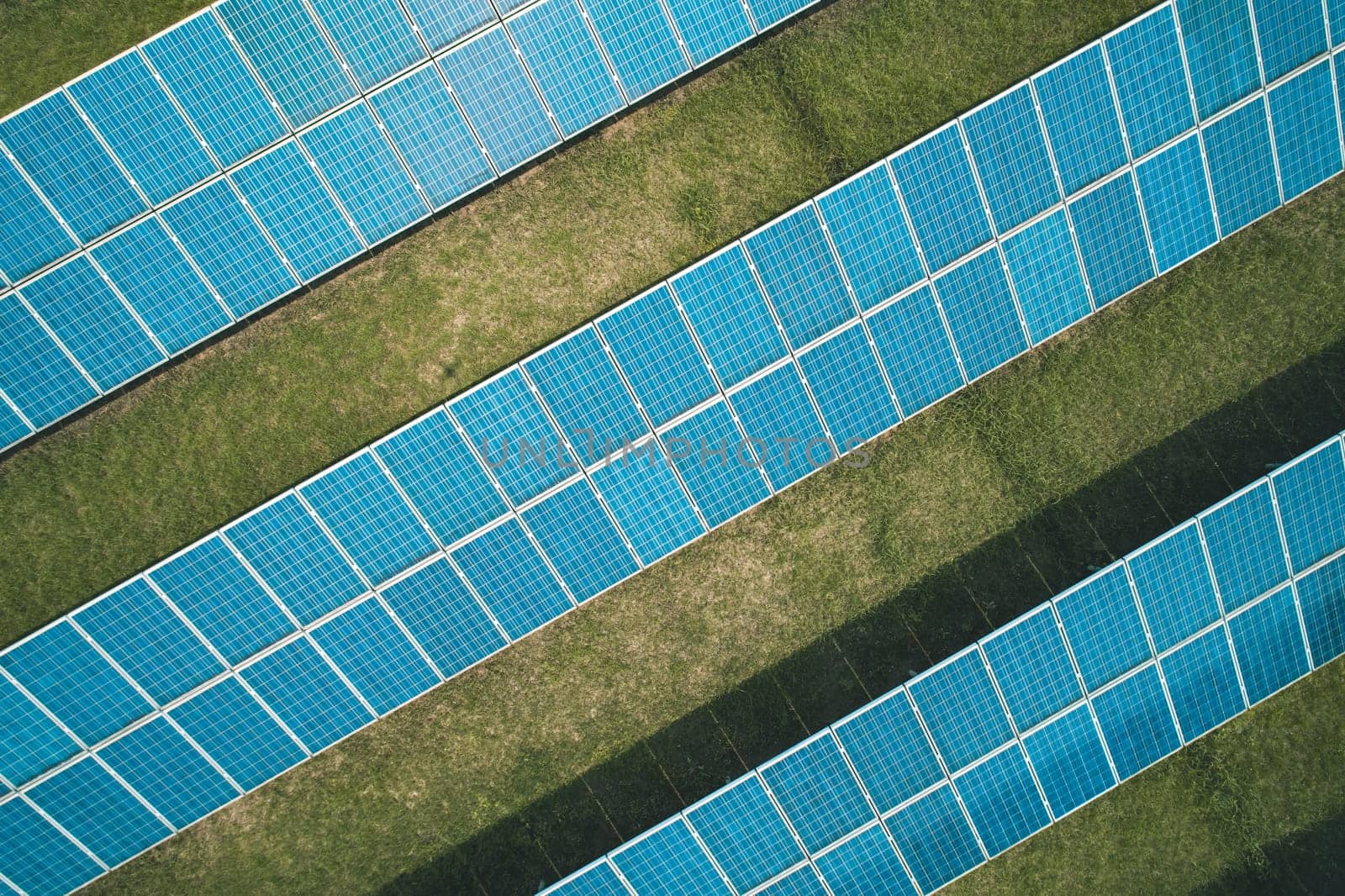 Aerial top down shot of solar panels farm on the green field. Renewable alternative green energy concept.